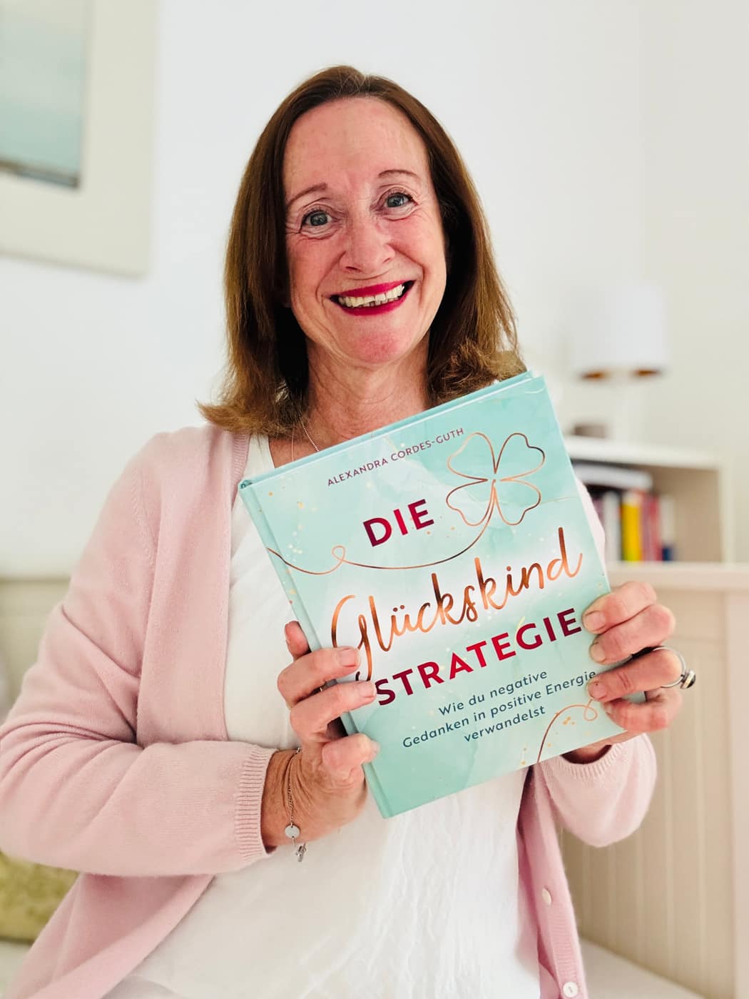 Alexandra Cordes-Guth hält ihr Buch Die Glückskindstrategie freudestrahlend in den Händen