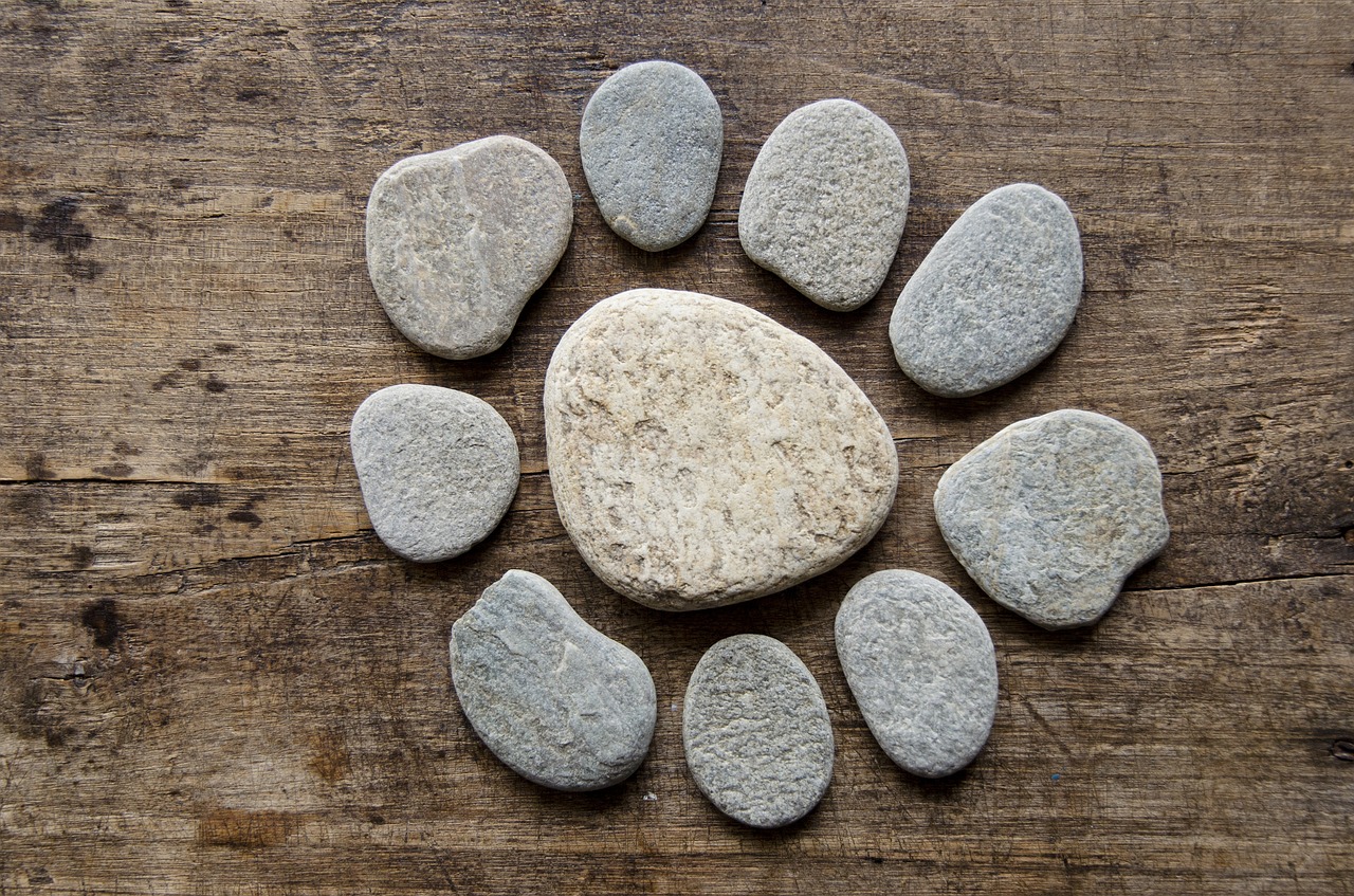 Steine liegen auf einem Holzbrett im Kreis als Sinnbild für den Weg in die eigene Mitte