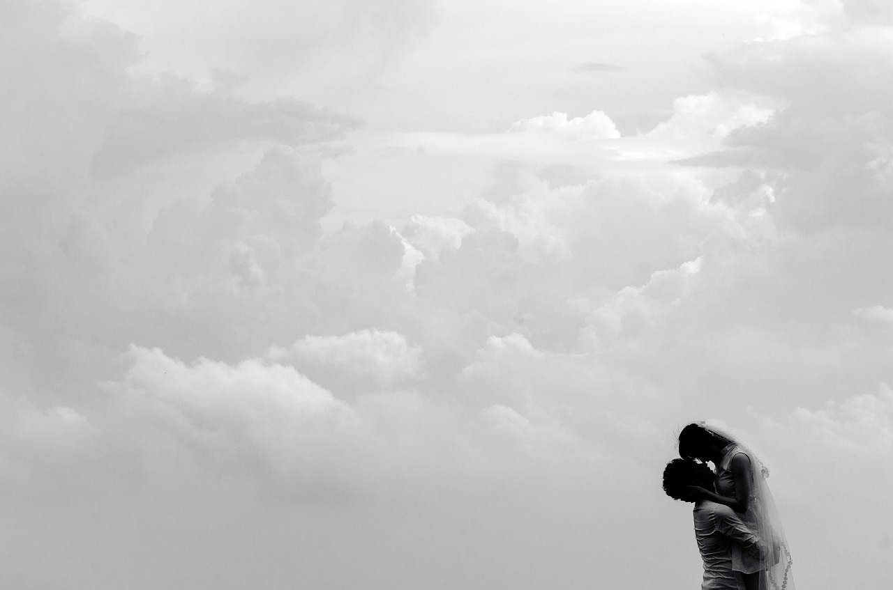 Mann und Frau fallen vor dem weiten Wolkenhimmel in die Arme als Sinnbild dafür, dass Meditation wie nach Hause kommen zu sich selbst ist.