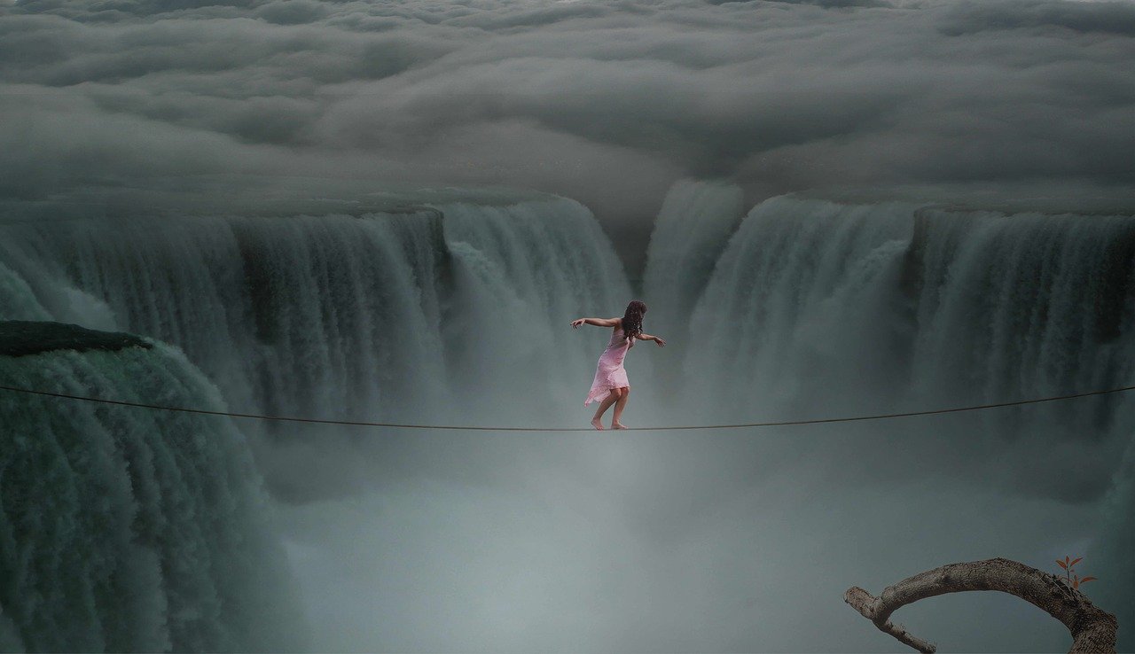 Frau balanciert mutig auf einem Seil über einem Wasserfall