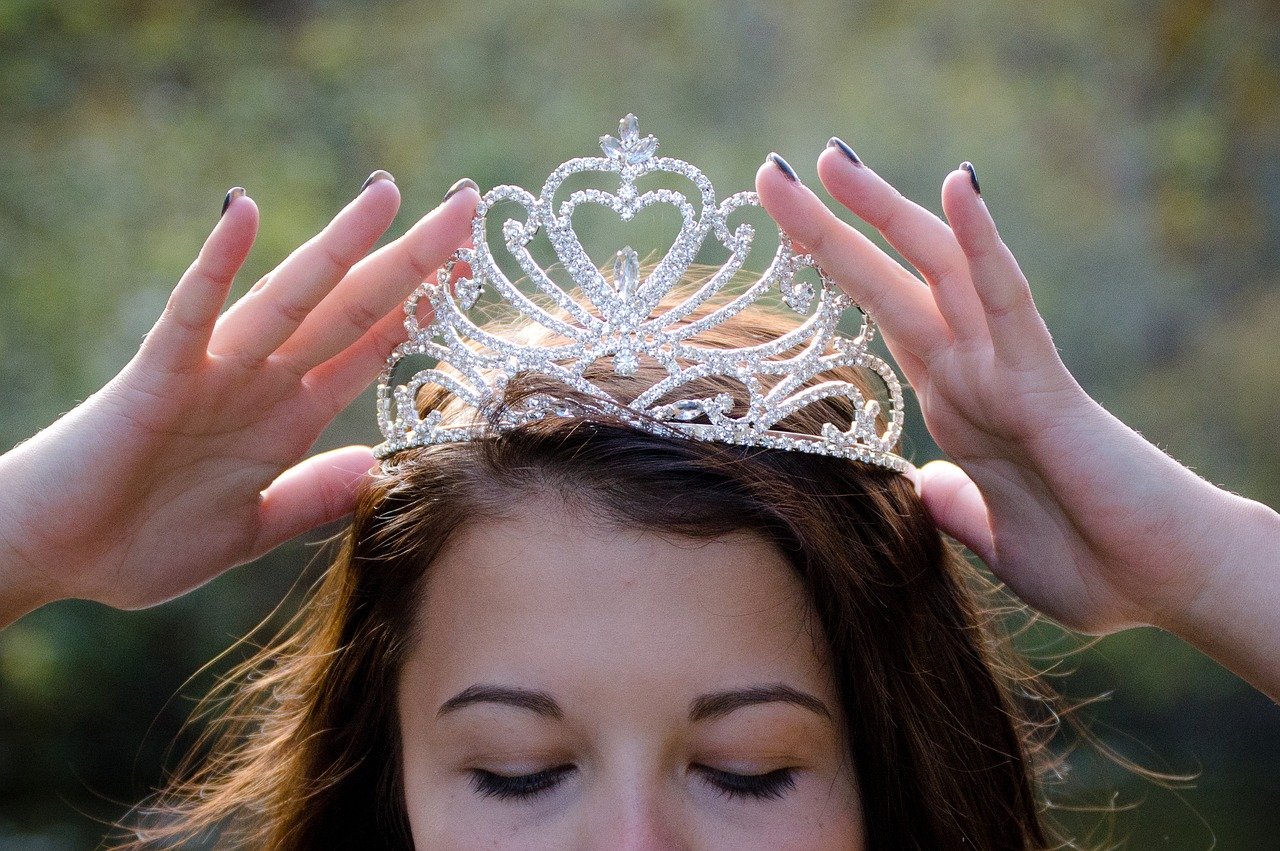 Frau setzt gerade eine Krone auf ihren Kopf