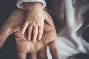 Kleine Kinderhand in eine große Hand gelegt als Sinnbild für das innere Kind