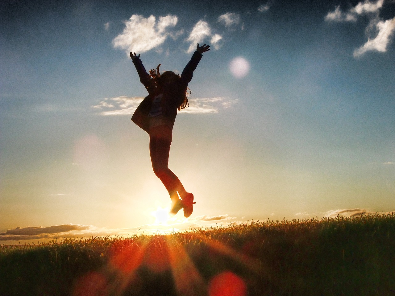 Mensch springt im Sonnenlicht in die Luft als Sinnbild für das Glück