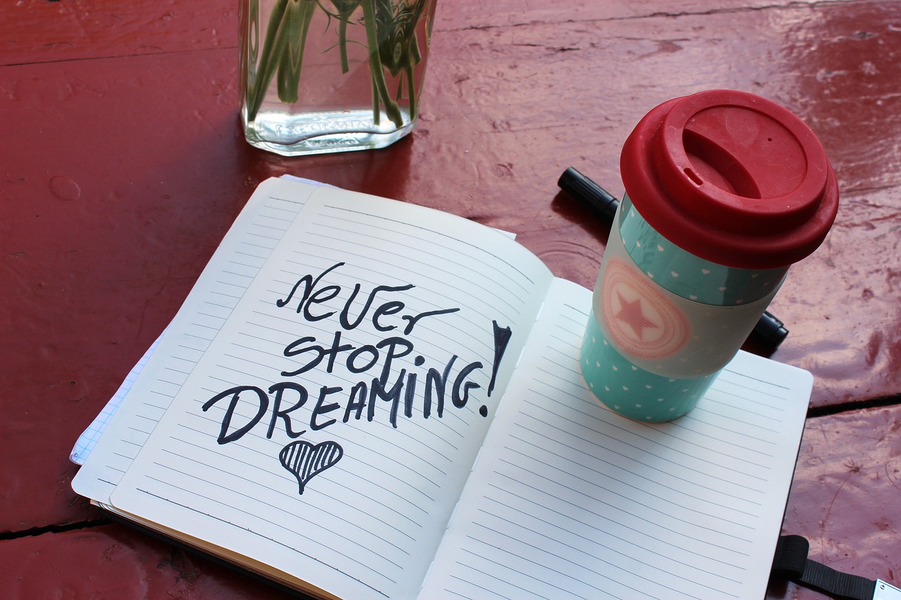 Becher auf einem Heft in dem steht: Never stop dreaming als Sinnbild für den Weg zum Traumjob